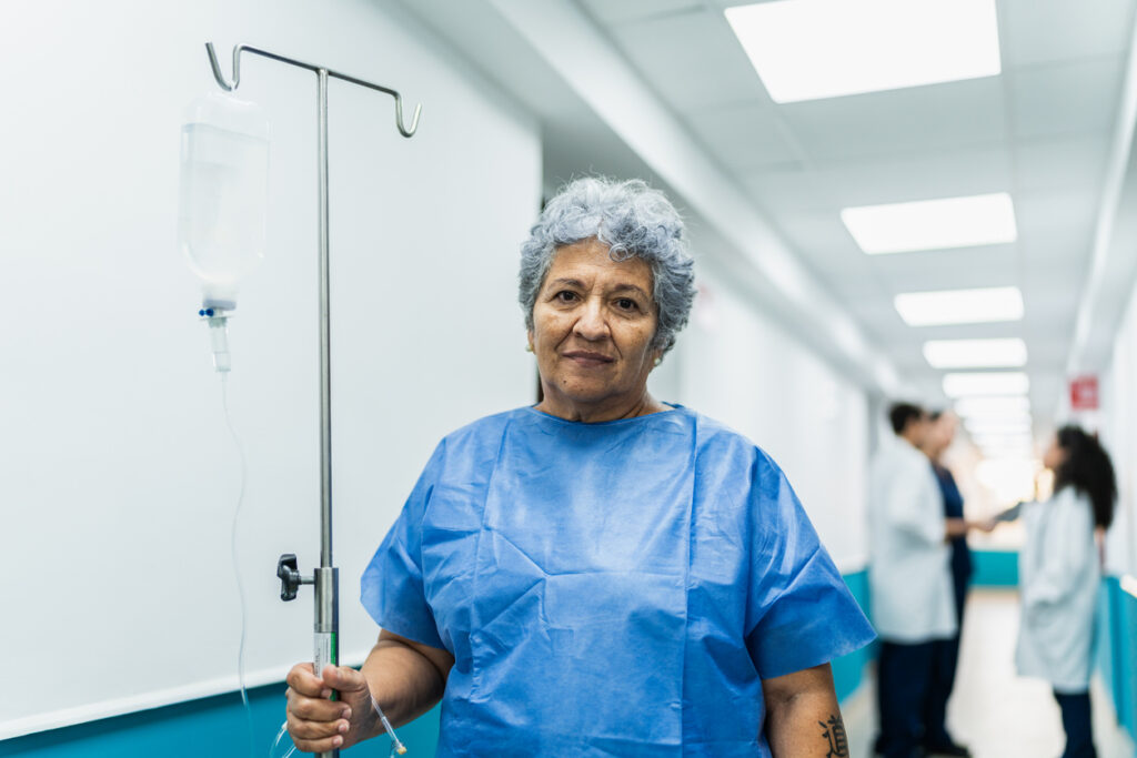 Portrait of senior patient woman taking serum at hospital corridor